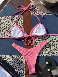 Detailed view of pink bikini set with floral texture on a geometric beach towel
