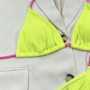 Neon green ribbed bikini set with pink straps shown flat lay on white blazer background