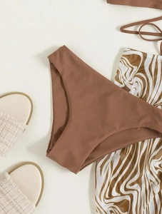 Dreiteiliger brauner Bikini mit gemustertem Sarong und passenden Strandsandalen