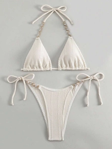 Detail eines cremefarbenen Ripp-Bikinis mit Strass-Metallketten und seitlichen Bändern