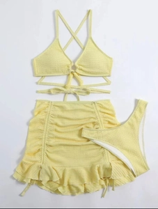Vue à plat d'un bikini trois pièces jaune pâle avec texture gaufrée et jupe à volants
