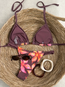 Two-piece floral bikini set with solid triangle top and flower print bottom on straw basket