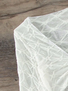 Detailed macro view of white bikini fabric featuring 3D star-shaped pleated texture
