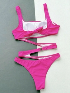 Flat lay of rose red monokini with tummy cross-ties and back bow tie detail