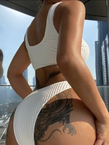 Detail of white ribbed knit bikini bottom with high cut leg design and textured fabric