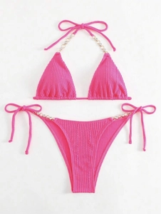 Detail eines pinkfarbenen Ripp-Bikinis mit Neckholder und Strasskettendekoration