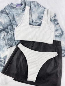 Flat lay of a 4-piece vacation set with rib-knit bikini, mesh top and PU skirt