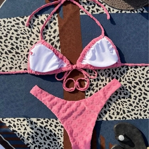 Pink two-piece halter bikini set with textured fabric and adjustable side tie bottoms