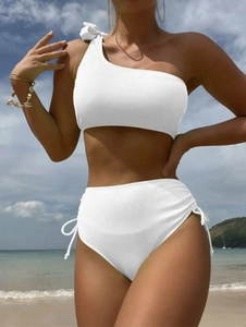 Close-up of white ribbed bikini featuring one-shoulder bow and side drawstring detail