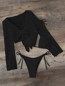 Detailed flat lay of black three-piece bikini set with geometric mesh cover-up fabric