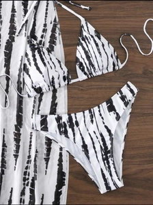 Flat lay of black and white tie-dye bikini three-piece set with a matching long cover-up