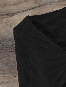 Close-up detail of the black hollowed-out textured fabric and intricate mesh pattern