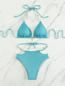 Bikini deux pièces bleu avec breloques perles et accents coquillages sur fond de marbre