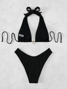 Close-up of black ribbed bikini fabric with decorative metal shell and starfish charms