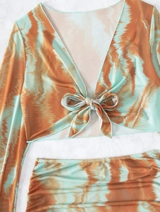 Détail du crop top en maille tie-dye avec nœud frontal et manches longues orange et bleu