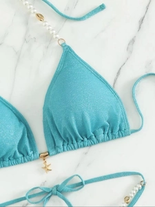 Détail du haut de bikini bleu brillant avec perles et pendentif en forme d'étoile