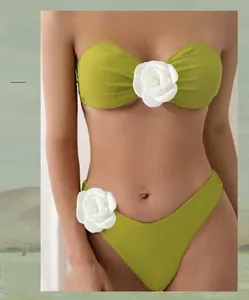 Detail of green bandeau bikini with white 3D floral accents on top and high-cut bottom