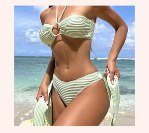 Primer plano del bikini acanalado verde claro con aro dorado y pareo a juego