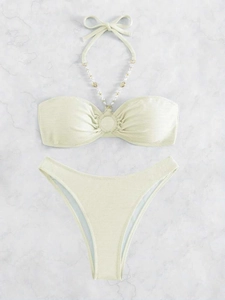 Dettaglio del tessuto bikini verde chiaro a nido d'ape con conchiglie e perline bianche