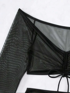 Détail de la tunique noire en maille transparente à manches longues et cordon de serrage