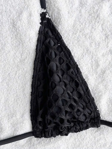 Macro detail of black bikini top with double-layer mesh texture and sleek ties