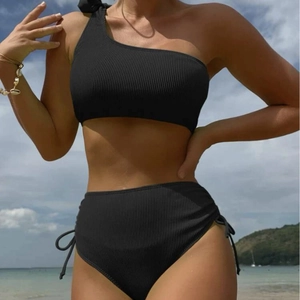 Black ribbed one-shoulder bikini set with side drawstring high-waist bottoms on the beach