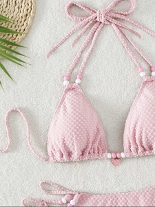 Haut de bikini rose à pois avec pendentif fraise et perles sur fond en peluche blanc