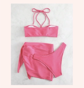 Detalle de bikini rosa de tres piezas con top halter y falda pareo de tejido acanalado