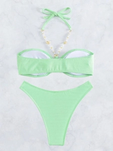 Dettaglio del bikini verde menta con motivo a spina di pesce, perle e conchiglie