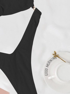 Détail macro du tissu noir texturé du maillot de bain avec anneaux métalliques dorés