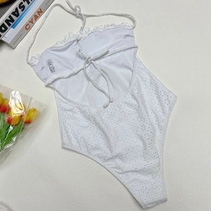 Flat lay of white halter neck swimsuit with embroidered cut-outs and tulip decor