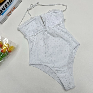 Detail of white Broderie Anglaise one-piece swimsuit with ruffled halter neck design