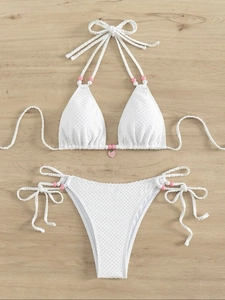Détail du bikini blanc texturé avec pendentif fraise et perles colorées décoratives