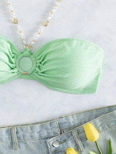 Dettaglio del bikini verde menta con catena decorativa di perle e conchiglie oro