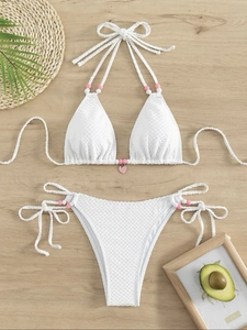 Bikini blanc gaufre avec bretelles perlées et pendentif fraise sur fond en bois naturel