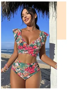 Détail d'un bikini à fleurs tropicales avec haut à volants et culotte haute sur la plage