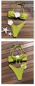Detailed view of avocado green bikini with white 3D flowers on a wooden deck
