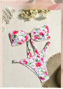 Vue à plat d'un bikini floral avec imprimés roses et bords festonnés sur sable fin