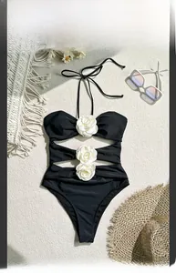 Detailed view of black halter swimsuit featuring 3D white rose flowers and cut-out designs