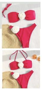 Flat lay of pink bikini with 3D white fabric flowers, sun hat and sunglasses on textured background