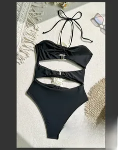 Flat lay of a sexy black one-piece cutout bikini with metal buckles and halter neck style