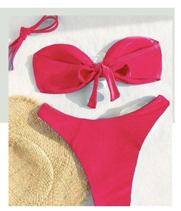 Flat lay of rose pink bikini set with bandeau bow top and high cut bottoms on white background