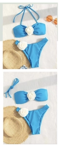 Detailed close-up of blue bikini with 3D white floral accents and high-cut bottoms