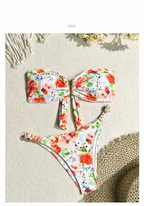 Bikini fleuri avec dentelle pompon blanche et anneau doré sur fond de sable fin