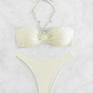 Set bikini a due pezzi a costine con spalline di perline su fondo di marmo