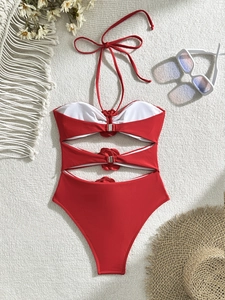 Close-up of red cutout one-piece swimsuit with silver metal buckles on waffle texture
