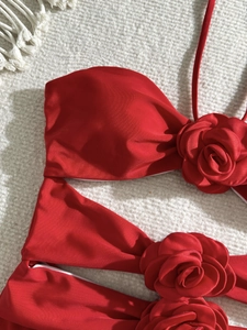 Detail of red one-piece swimsuit featuring handmade 3D fabric rose floral accents