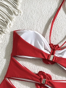 Detail of red one-piece swimsuit featuring 3D floral accents and silver metal buckles