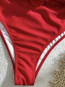 Detailed macro view of bright red bikini bottom with white lining and precise stitching