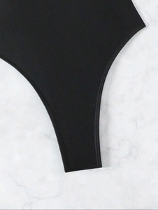 Detail view of high-cut leg opening and premium stitching on a black one-piece swimsuit